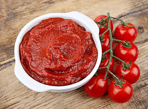 Tomato paste with ripe tomatoes on wooden tables